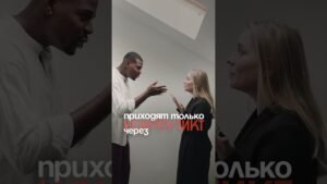 Two professionals—a man and a woman—face each other in a heated discussion, hands gesturing as they talk, with Cyrillic text overlaid in the center.