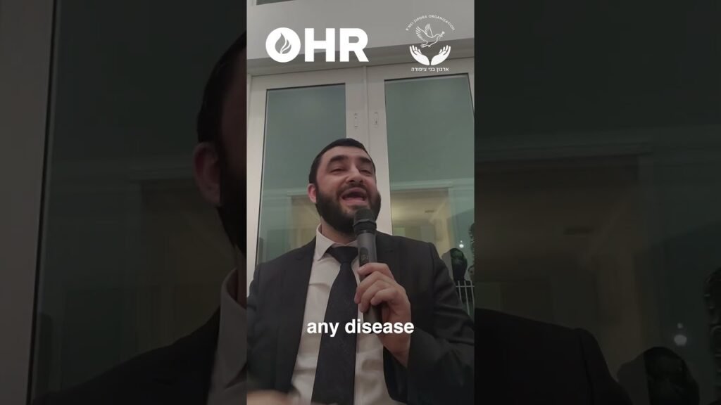 Man in a suit speaking into a handheld microphone at an indoor event, with OHR logo visible at top center and the caption 'any disease'.
