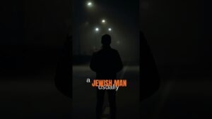 Back view of a man in a dark coat standing on a dimly lit night street, with bold orange text reading 'JEWISH MAN' overlaid across the center.