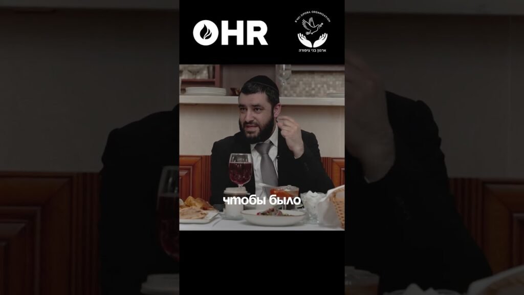 Bearded man in a suit and kippah speaks at a dinner table with a glass of wine; two logos (HR and a Hebrew organization) are visible at the top, with the subtitle "чтобы было" on screen.