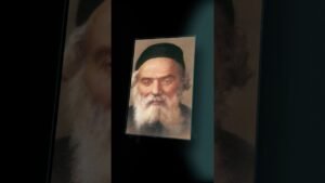 Tilted framed portrait of an elderly man with a white beard and black hat on a dark backdrop.