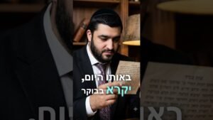Bearded man in a suit and kippah reading a Hebrew manuscript in a library.