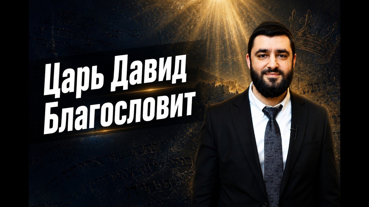 Man in a dark suit with a white shirt and patterned tie stands to the right, in front of a backdrop with large white Cyrillic text that reads “Царь Давид Благословит.”