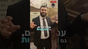 Smiling man in a dark suit and gray tie, gesturing with his hands inside a stone-walled room; Hebrew caption and HR logo overlaid.