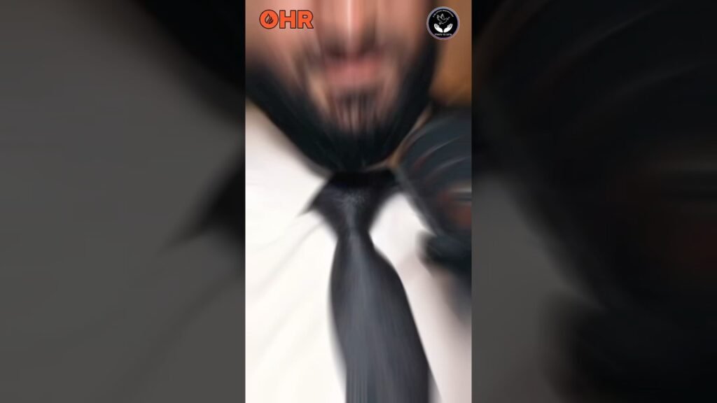 Blurred close-up of a man in a white shirt and black tie, motion blur with orange OHR logo at the upper left and a circular badge at the upper right.
