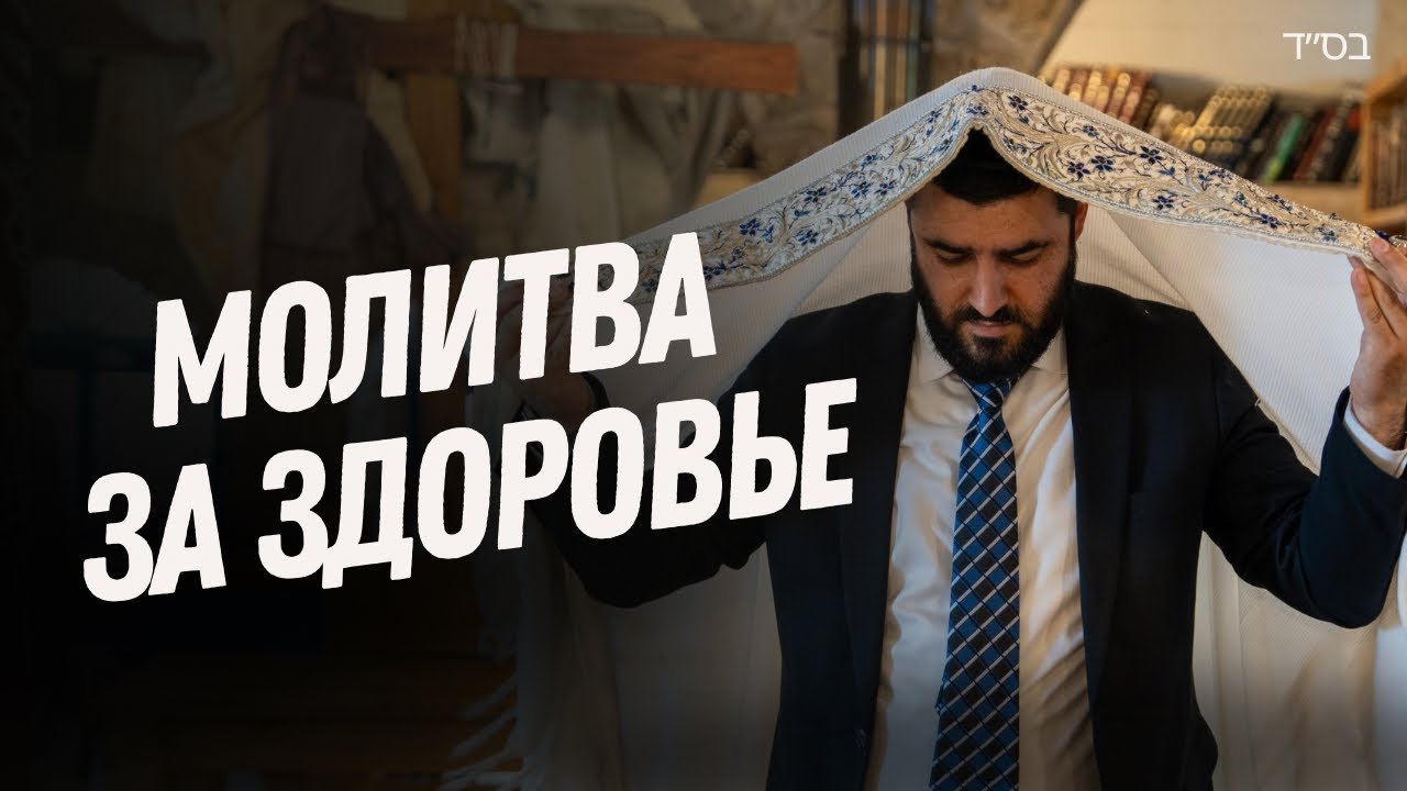 Man in a suit holds a prayer shawl over his head, signaling a prayer for health.