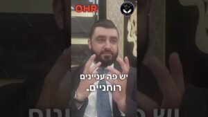 Bearded man in a suit gesturing with his hands, with Hebrew caption overlay and two logos at the top corners (OHR and circular badge).