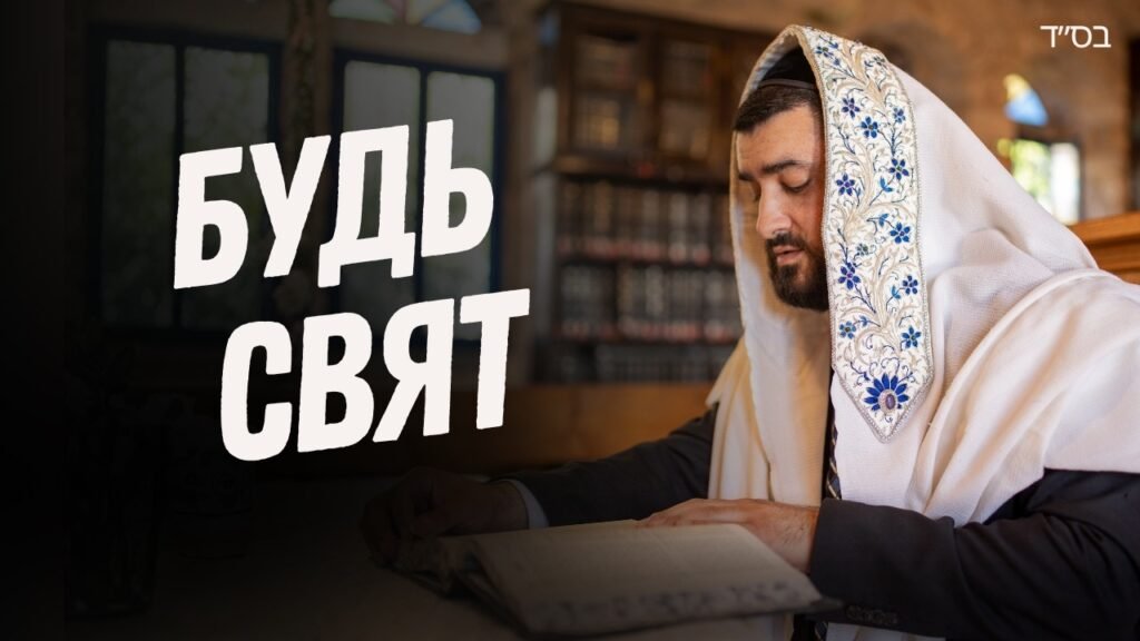 Jewish man in a white prayer shawl reading a Torah in a synagogue; large Russian text 'Будь Свят' overlays the scene.